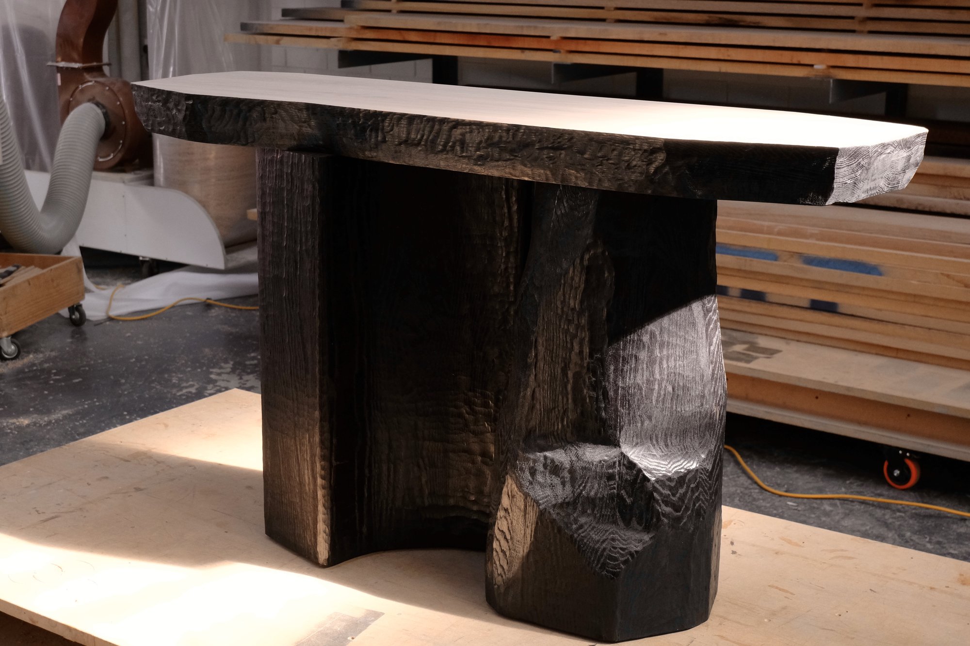 Relief Console, a dark hand-carved oak console with a pale smooth top, seen in three quarter view