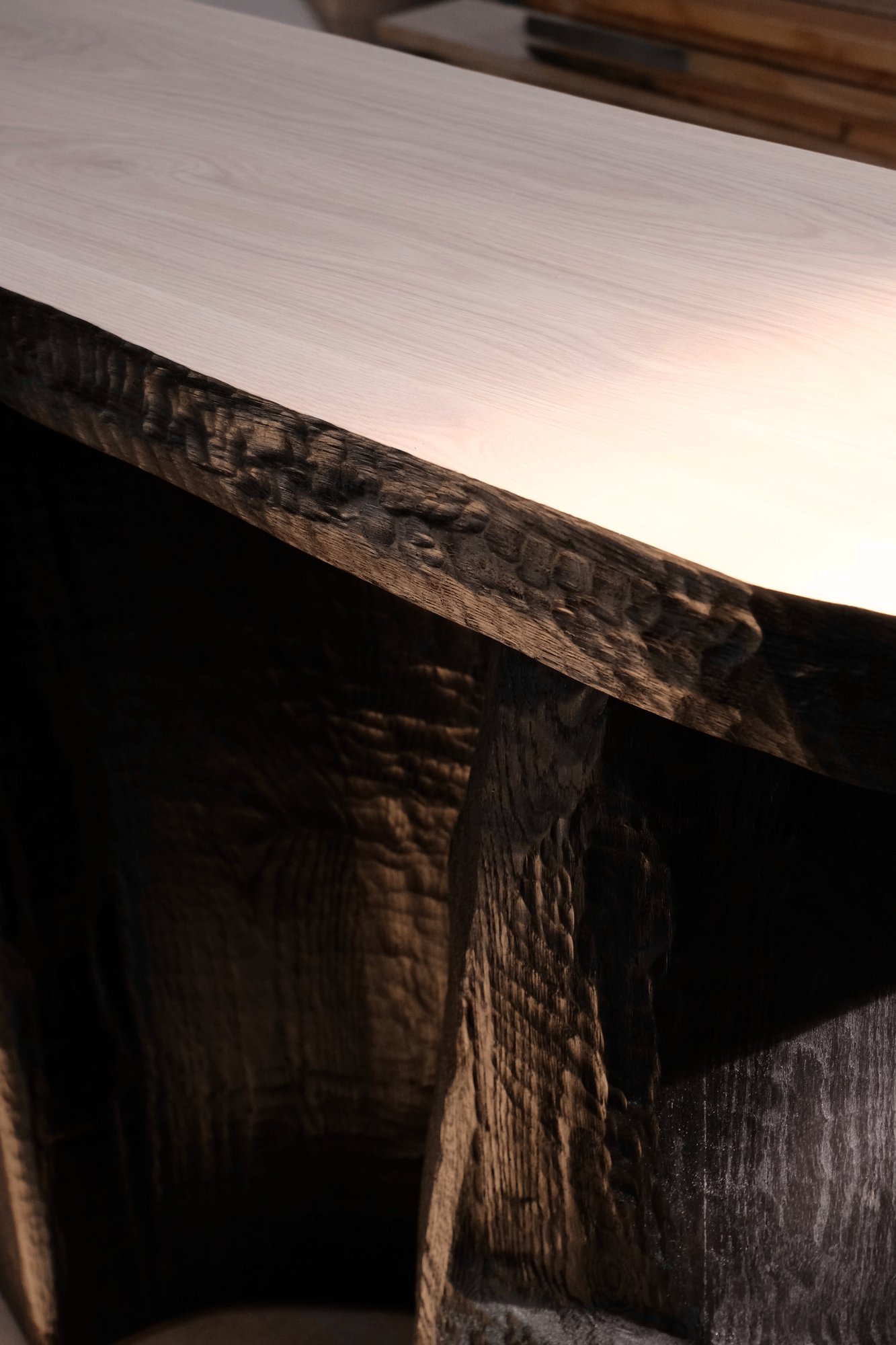 Relief Console detail of the carved edge where the pale top meets the blackened base